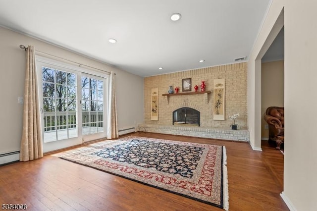 living area with baseboards, a baseboard heating unit, wood finished floors, and visible vents
