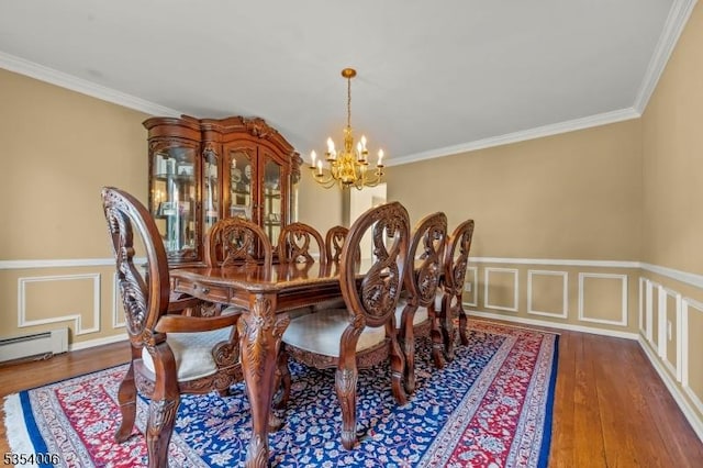 dining area with crown molding, wood finished floors, a notable chandelier, and a wainscoted wall