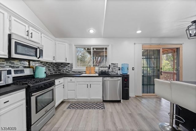 kitchen featuring a sink, dark countertops, stainless steel appliances, and a healthy amount of sunlight