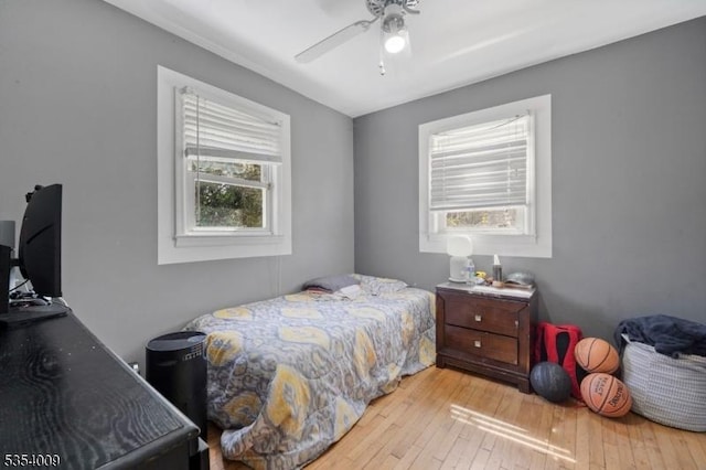 bedroom with ceiling fan, multiple windows, and hardwood / wood-style floors