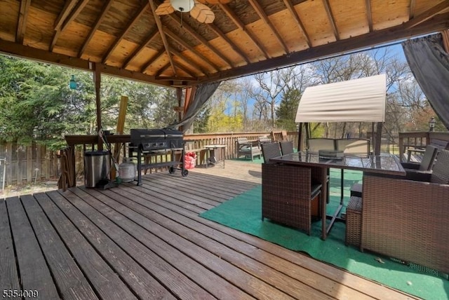 wooden terrace with a fenced backyard, a ceiling fan, and outdoor dining area