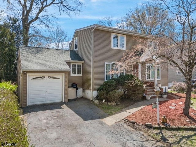 colonial home with a garage, a shingled roof, and aphalt driveway