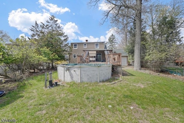 back of house featuring a lawn, a deck, and an outdoor pool