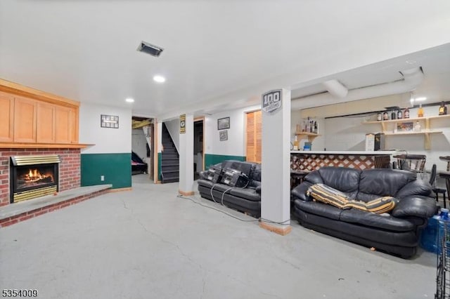 living room with finished concrete flooring, a brick fireplace, stairs, recessed lighting, and visible vents