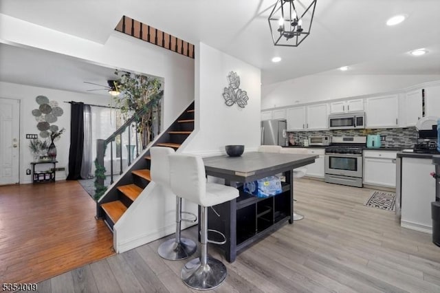 kitchen featuring dark countertops, white cabinetry, light wood-style flooring, appliances with stainless steel finishes, and backsplash