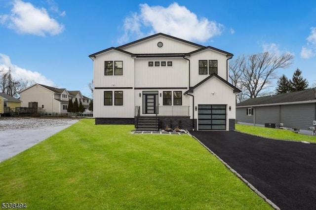view of front of home featuring driveway, a front yard, an attached garage, and central air condition unit