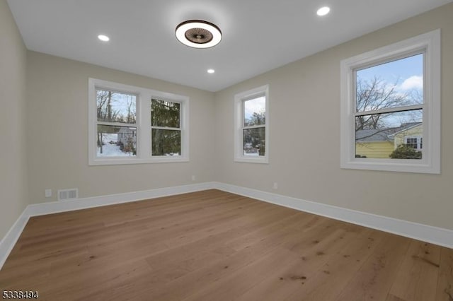 unfurnished room featuring baseboards, visible vents, and wood finished floors