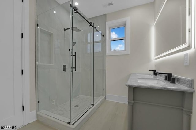 bathroom featuring baseboards, visible vents, a shower stall, and vanity