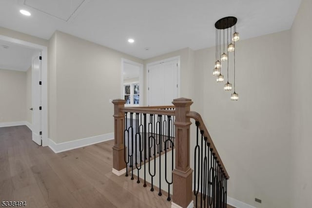corridor featuring an upstairs landing, wood finished floors, and baseboards