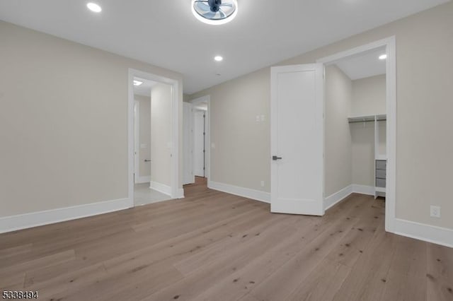 interior space with a closet, baseboards, recessed lighting, light wood finished floors, and a spacious closet