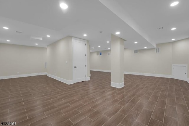 finished basement featuring baseboards, visible vents, and dark wood-type flooring