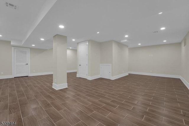 finished below grade area featuring dark wood-type flooring, visible vents, recessed lighting, and baseboards