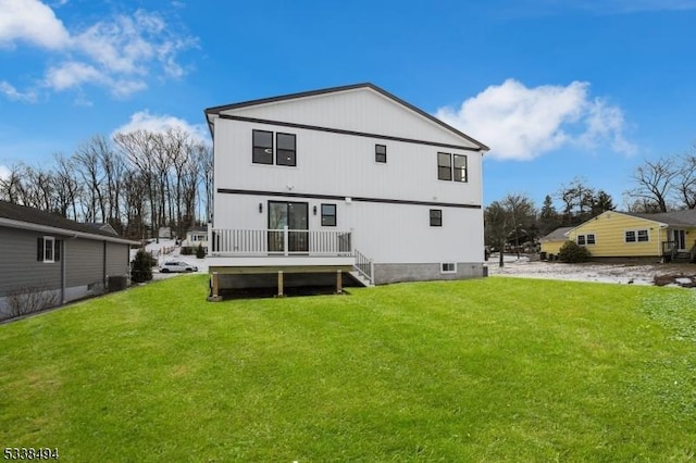 rear view of property featuring a wooden deck and a lawn