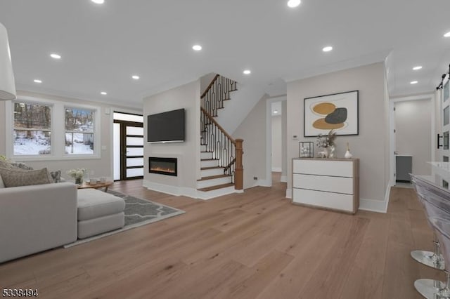 living room with stairway, a glass covered fireplace, light wood-type flooring, and baseboards