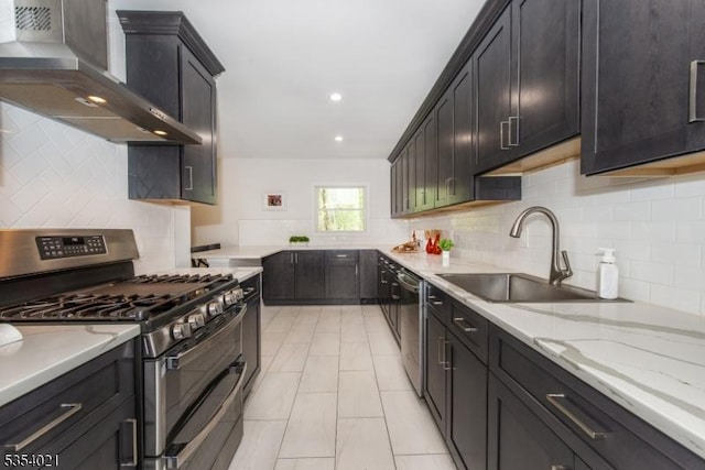 kitchen with wall chimney range hood, light stone counters, a sink, backsplash, and stainless steel appliances