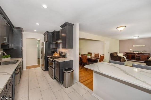 kitchen featuring a sink, appliances with stainless steel finishes, light stone counters, and open floor plan