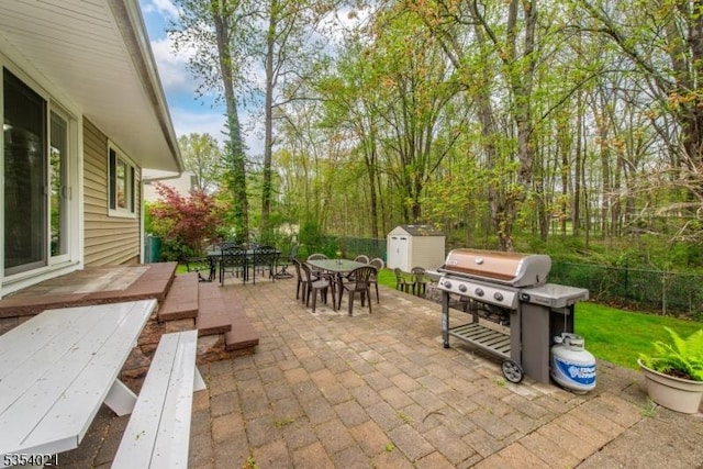 view of patio / terrace with area for grilling, an outbuilding, a fenced backyard, a shed, and outdoor dining space