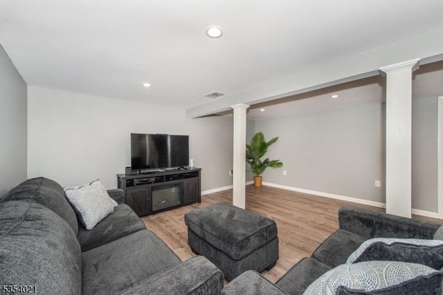 living area featuring recessed lighting, baseboards, decorative columns, and light wood finished floors