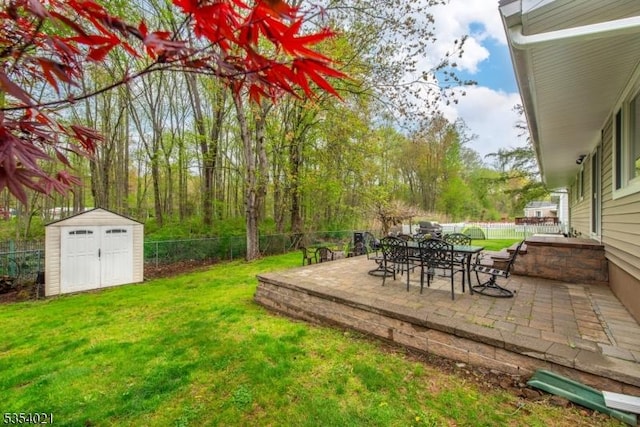 view of yard with a fenced backyard, a storage unit, an outbuilding, and a patio area