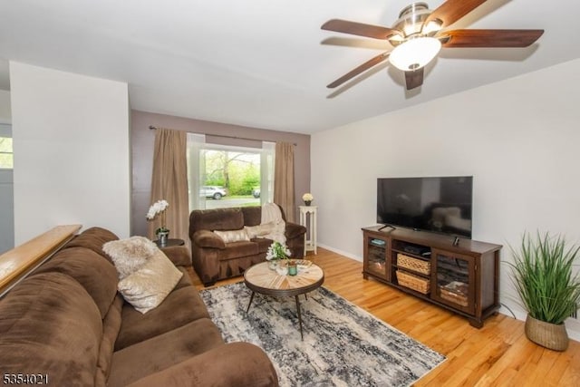 living area featuring ceiling fan, baseboards, and light wood-style floors