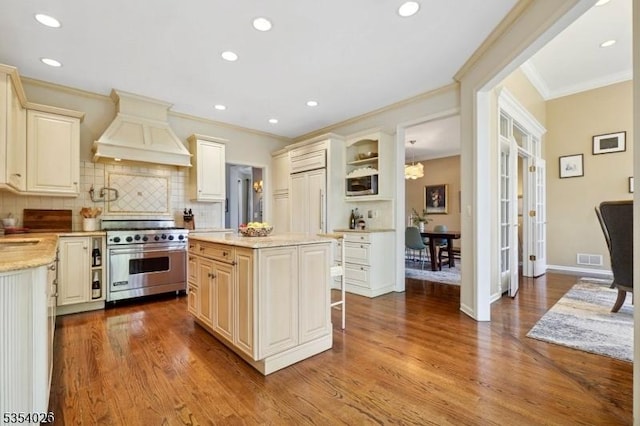 kitchen with crown molding, high end appliances, tasteful backsplash, premium range hood, and dark wood-type flooring
