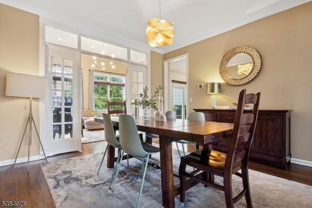 dining room with baseboards, ornamental molding, and wood finished floors