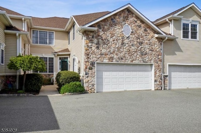 townhome / multi-family property with aphalt driveway and stone siding