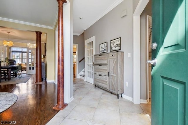 hallway with decorative columns, crown molding, light tile patterned floors, baseboards, and stairway