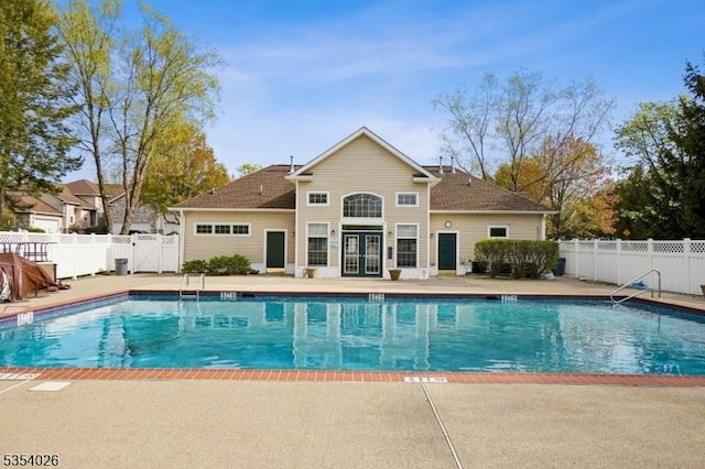 community pool with a patio, fence, and a gate