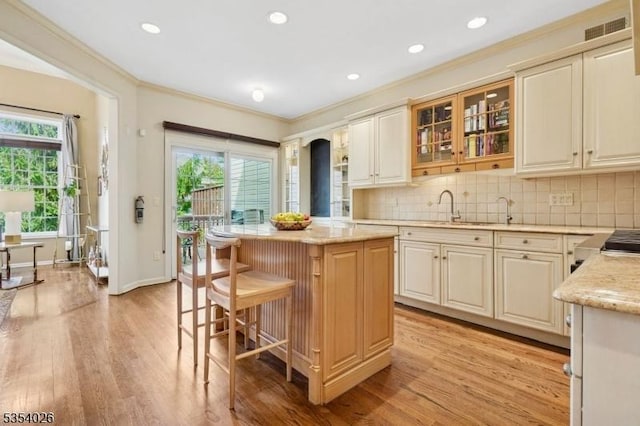kitchen with a sink, crown molding, light wood-style floors, and a wealth of natural light