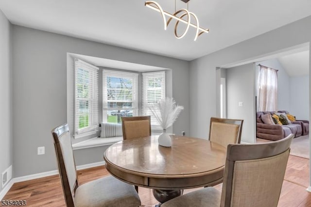 dining room featuring light wood-type flooring, baseboards, visible vents, and an inviting chandelier