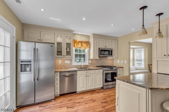 kitchen featuring a sink, appliances with stainless steel finishes, backsplash, and a healthy amount of sunlight