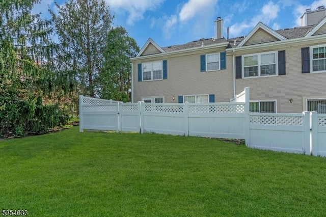 back of property featuring a lawn, a chimney, and fence private yard