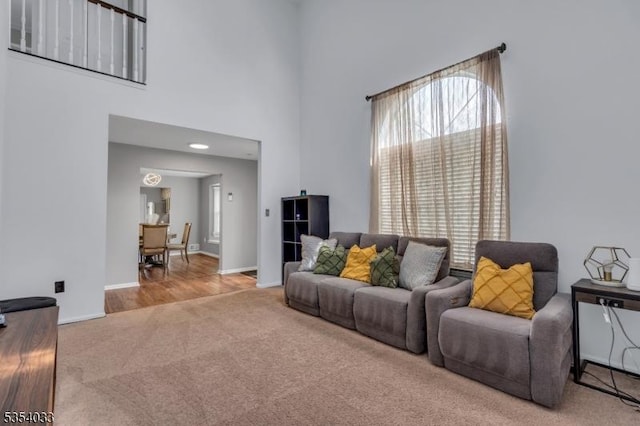 carpeted living room with baseboards and a high ceiling