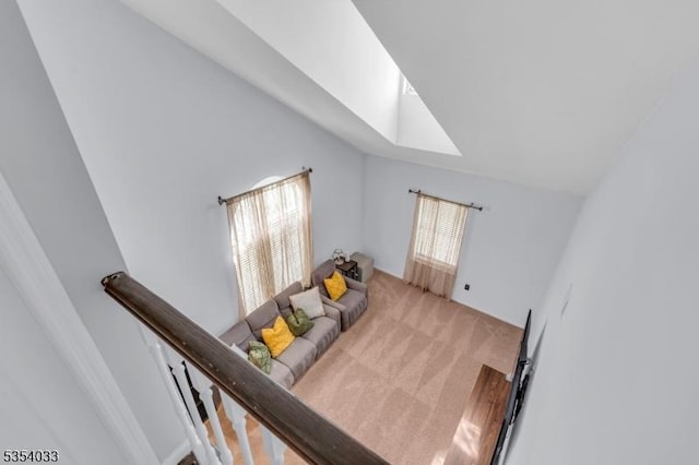 carpeted living area with lofted ceiling with skylight