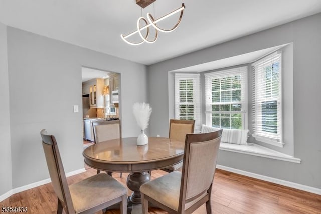 dining space featuring light wood-type flooring, baseboards, and an inviting chandelier