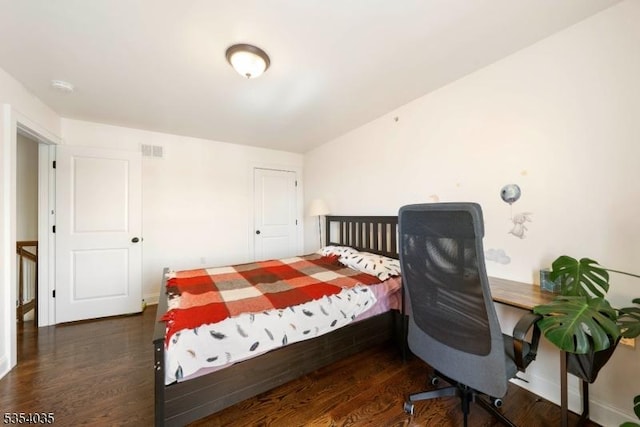 bedroom featuring baseboards, visible vents, and wood finished floors