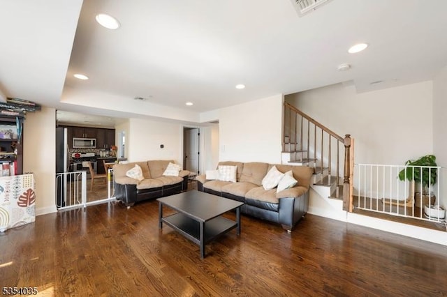 living room featuring recessed lighting, visible vents, wood finished floors, and stairway