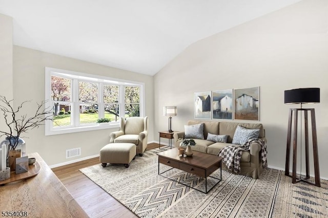 living room with visible vents, baseboards, lofted ceiling, and wood finished floors