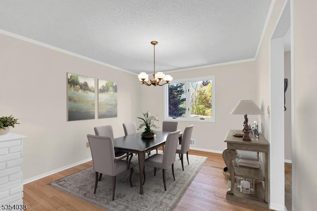 dining space featuring baseboards, a chandelier, ornamental molding, and light wood-style flooring
