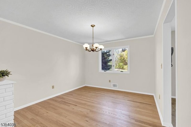 spare room with crown molding, an inviting chandelier, light wood-style flooring, baseboards, and visible vents