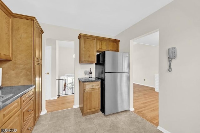 kitchen featuring dark countertops, baseboards, and freestanding refrigerator