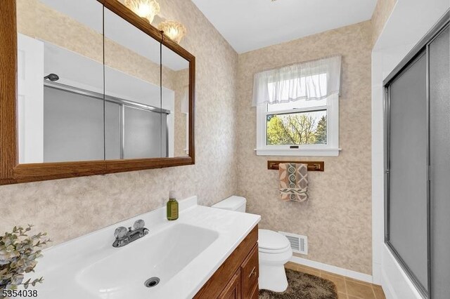 bathroom with a shower with shower door, vanity, toilet, tile patterned floors, and visible vents