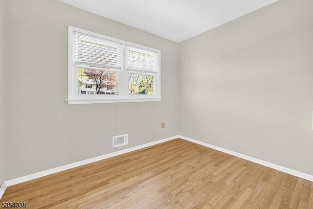 spare room with baseboards, visible vents, and light wood-style flooring