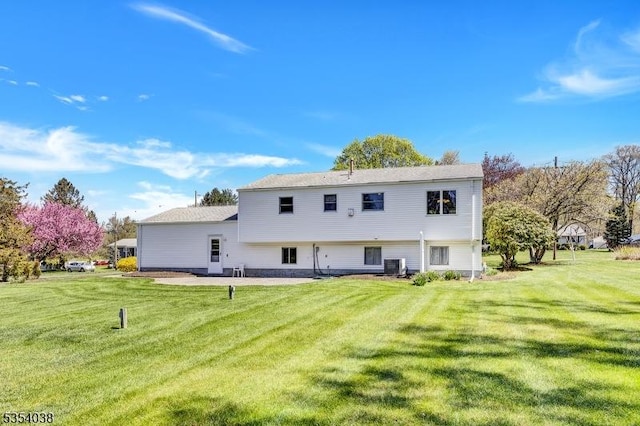 rear view of property featuring central AC and a yard
