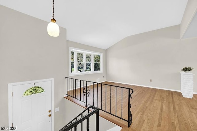 foyer featuring baseboards, light wood-style flooring, and vaulted ceiling