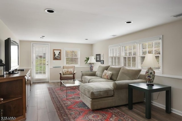 living room with baseboards, visible vents, and wood finished floors