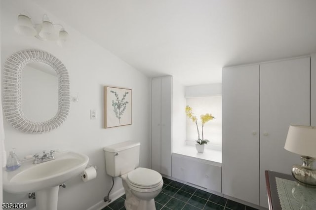 half bathroom with a sink, tile patterned floors, and toilet