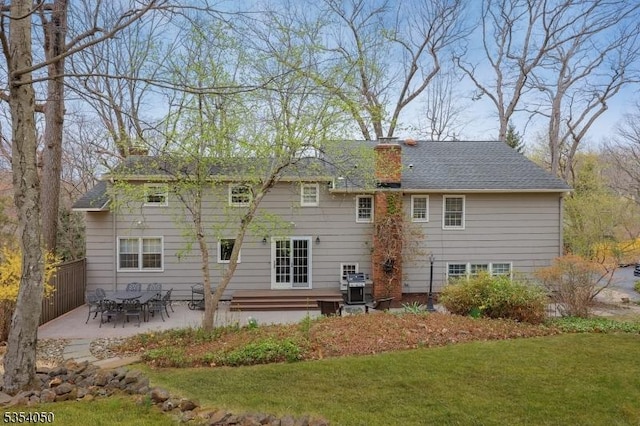 rear view of property featuring a patio, a lawn, and a chimney