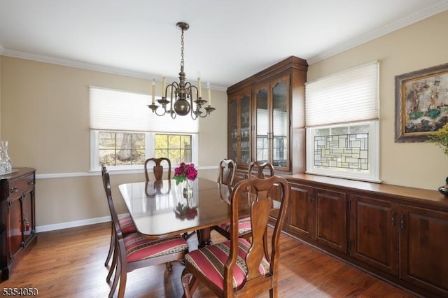 dining room featuring an inviting chandelier, ornamental molding, baseboards, and wood finished floors